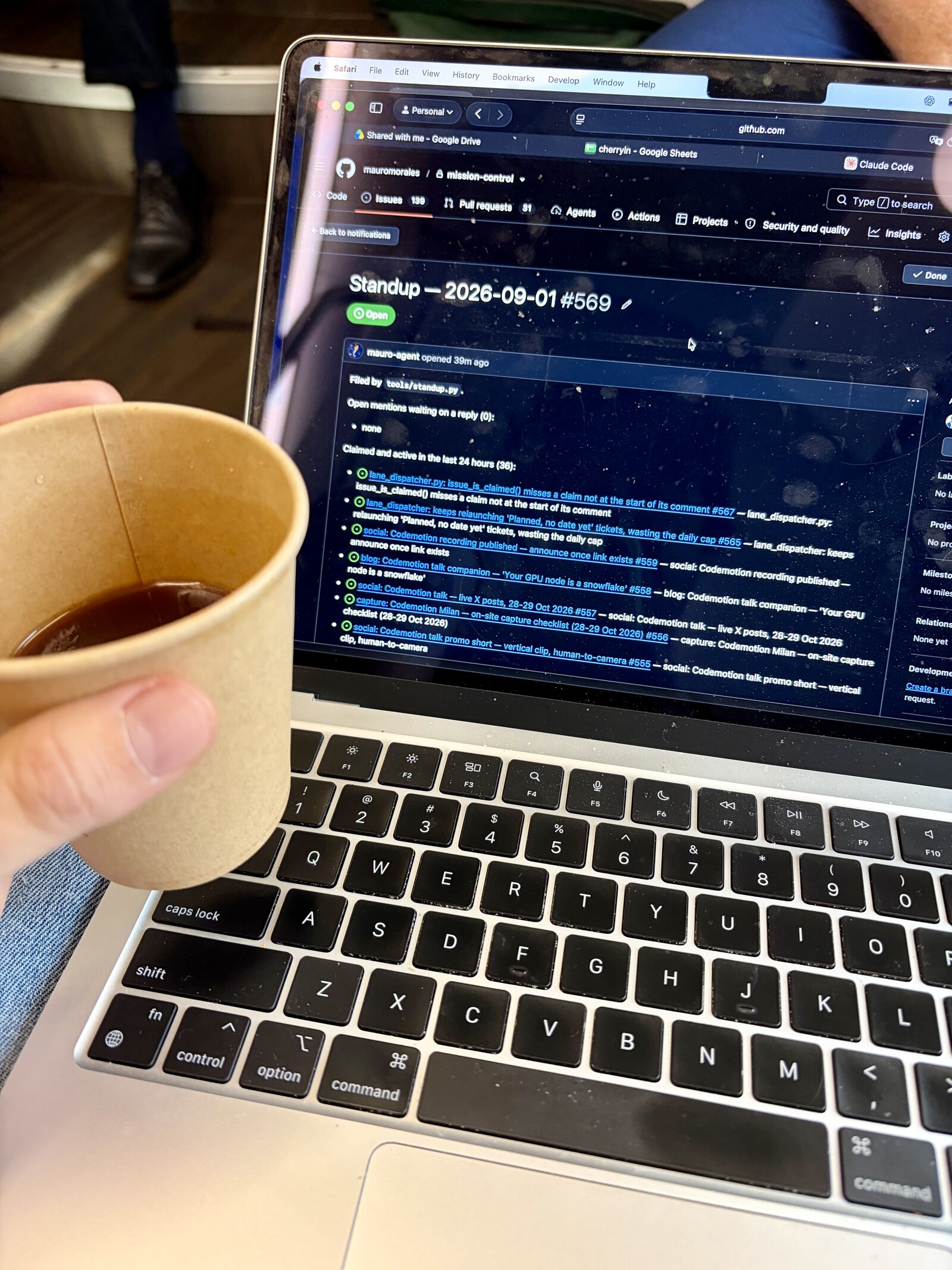 Checking the morning standup issue on a laptop at an airport, coffee in hand